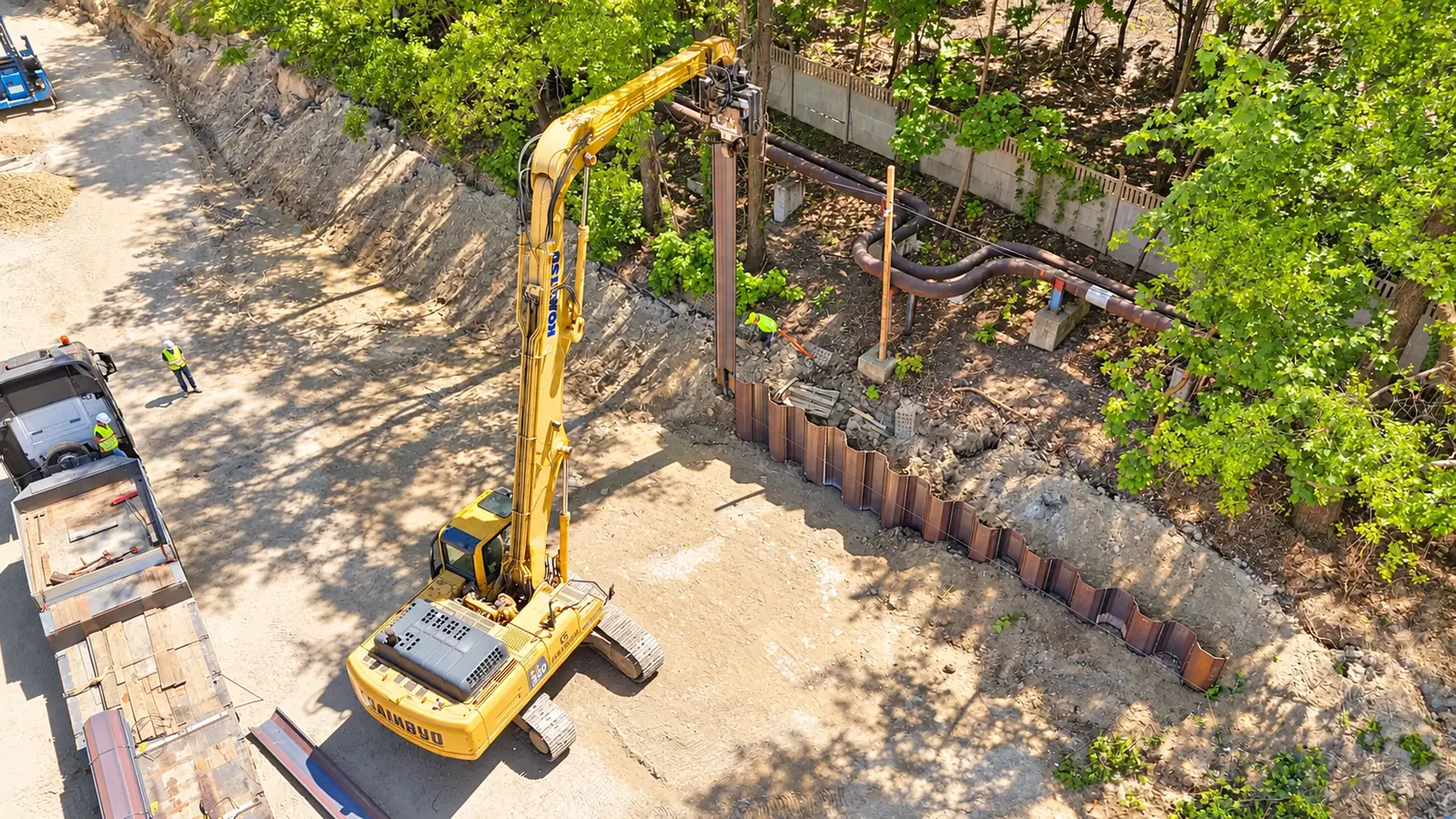 Komatsu z wibromłotem przy łukowo poprowadzonej ściance z grodzic stalowych.